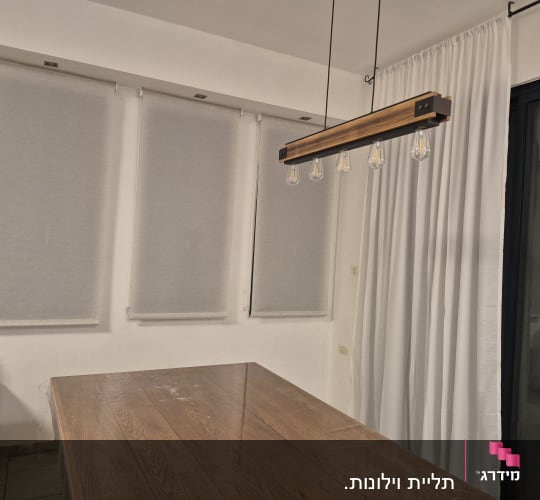 מנורת תלייה מעל שולחן עץ בחדר עם וילונות